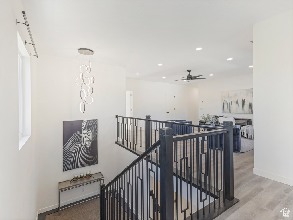 Hallway with an upstairs landing, recessed lighting, wood finished floors, and baseboards