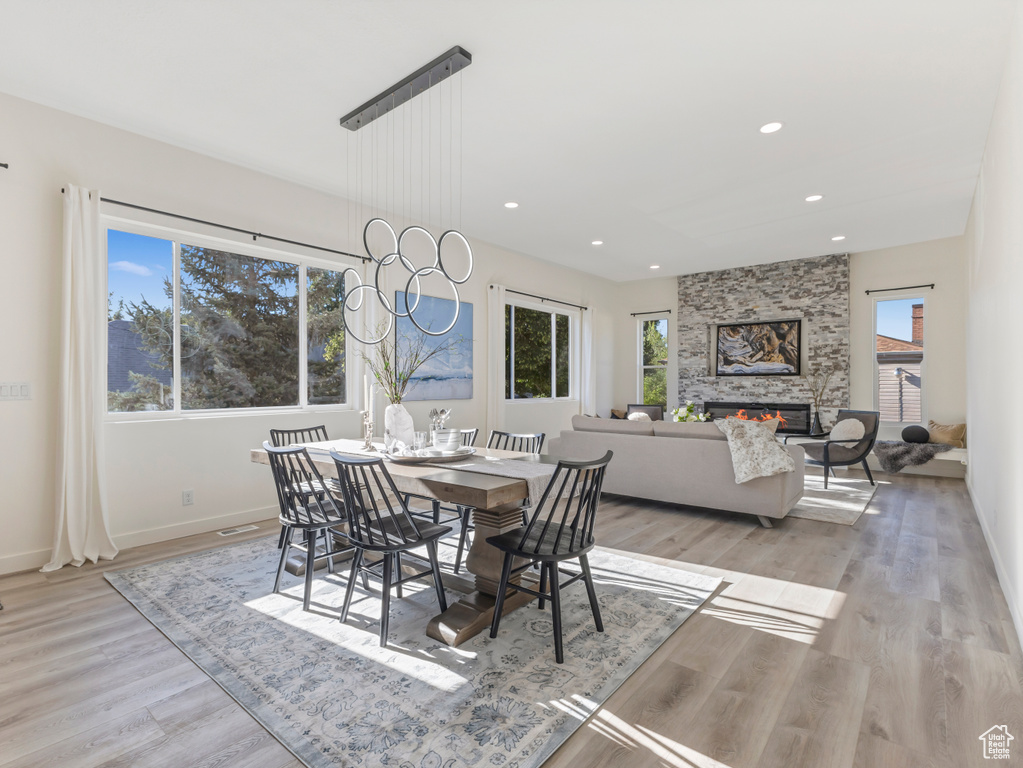 Dining room with plenty of natural light, light wood-style flooring, recessed lighting, baseboards, and a fireplace