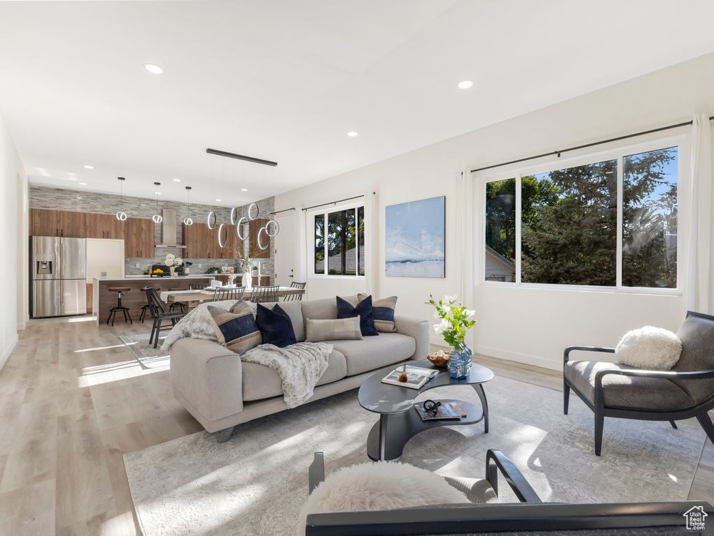 Living room with healthy amount of natural light, light wood finished floors, and recessed lighting