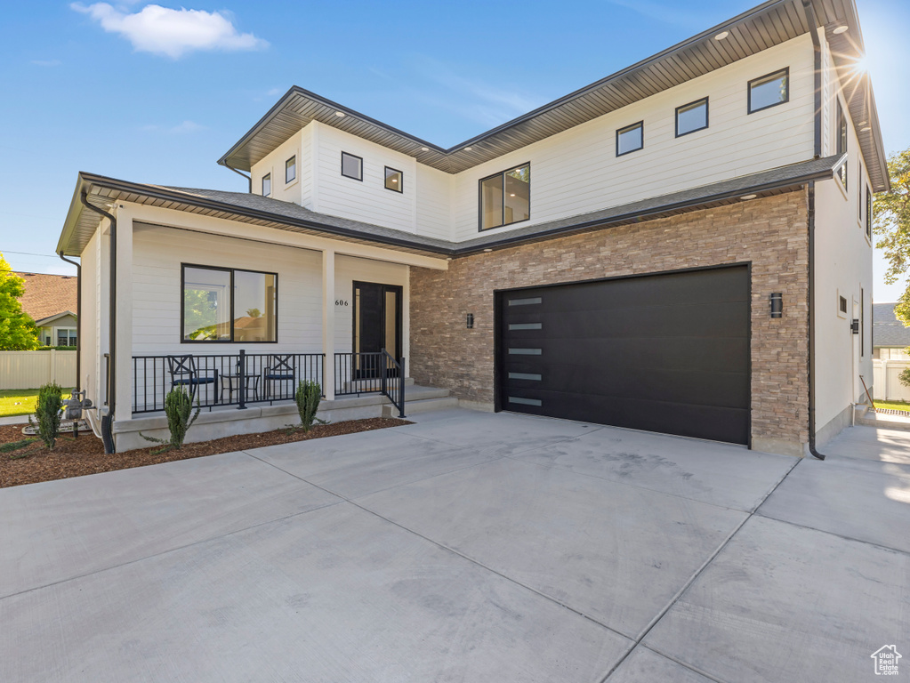 View of front facade featuring covered porch, an attached garage, and driveway
