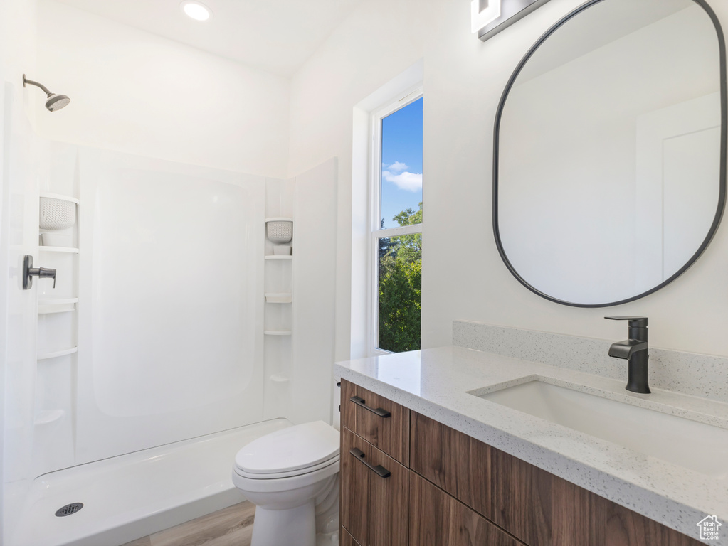 Full bath featuring vanity, a shower stall, toilet, wood finished floors, and recessed lighting