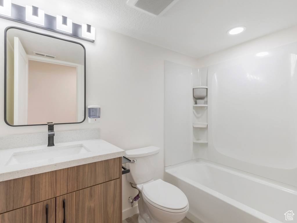 Bathroom with toilet, vanity, and recessed lighting