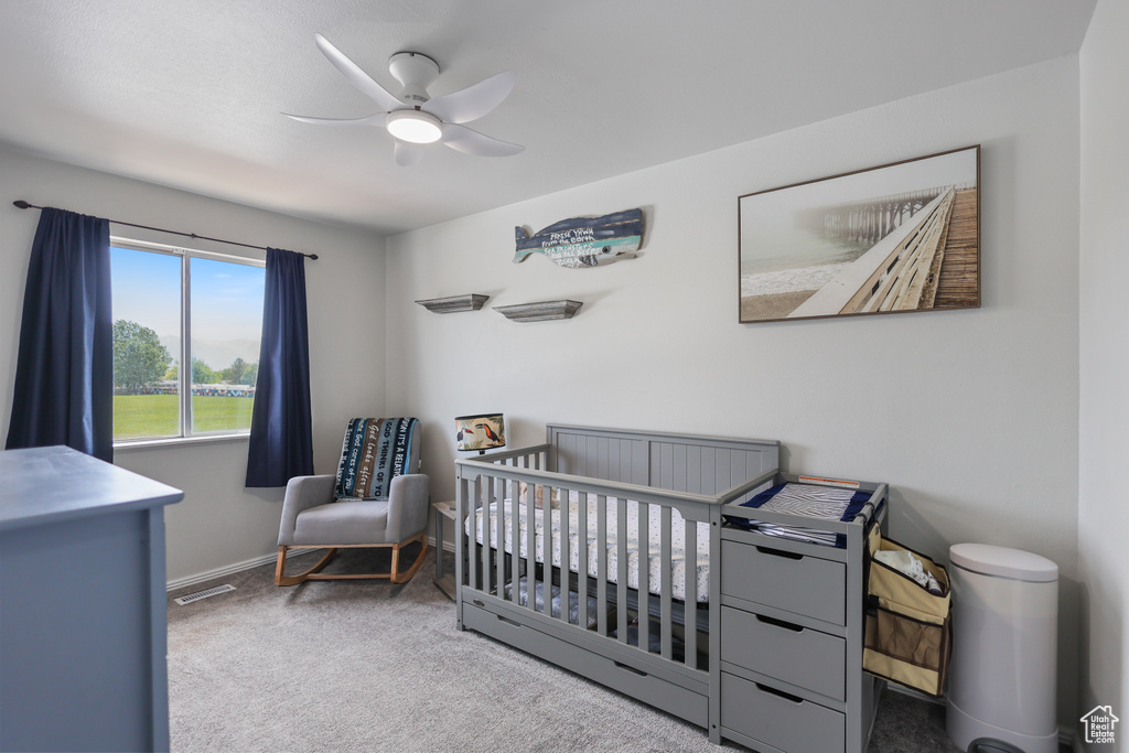 Bedroom with carpet, a crib, a ceiling fan, and baseboards