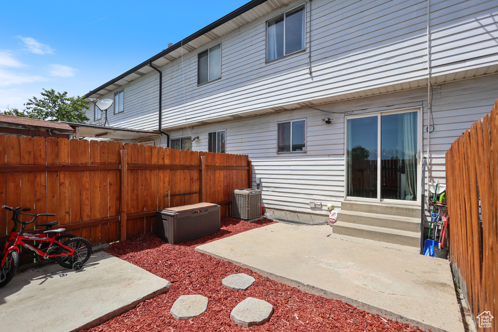 Back of house with entry steps, fence, cooling unit, and a patio