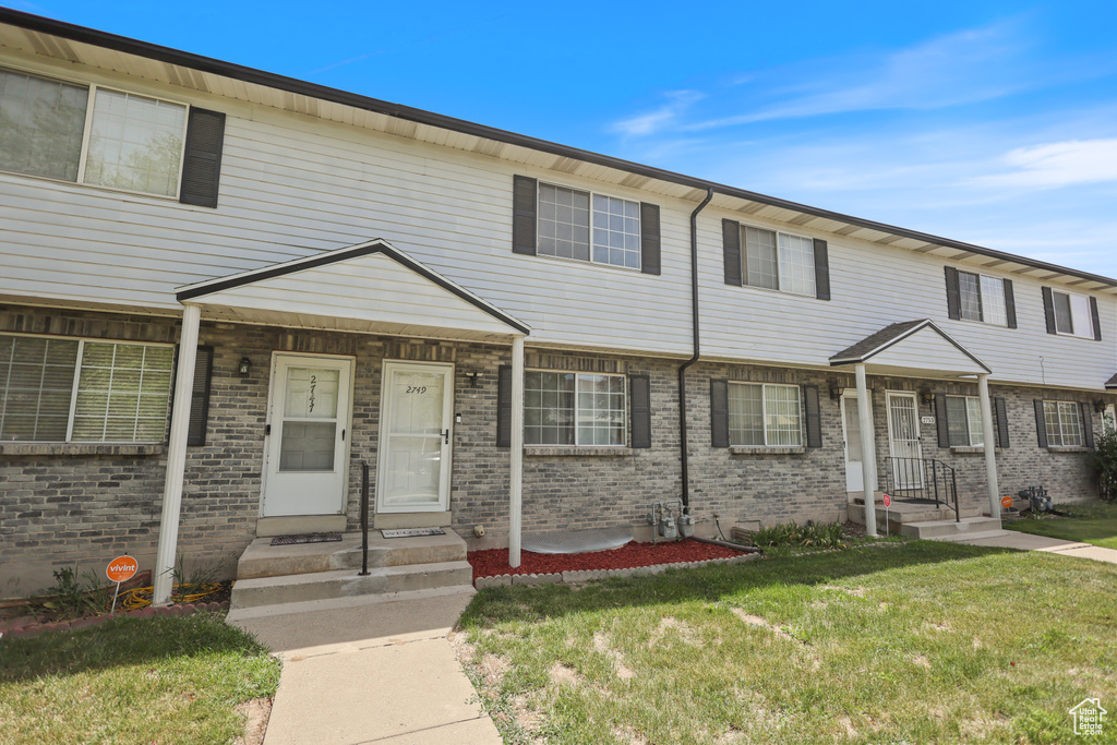 View of property with a front yard and brick siding