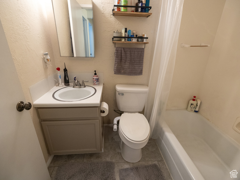 Bathroom with toilet, vanity, tile patterned floors, and shower / bath combo