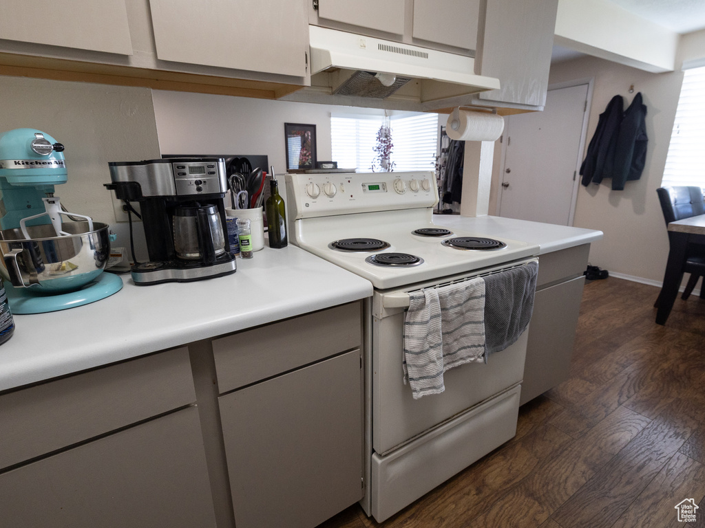 Kitchen featuring white electric range oven, under cabinet range hood, dark wood finished floors, light countertops, and gray cabinetry