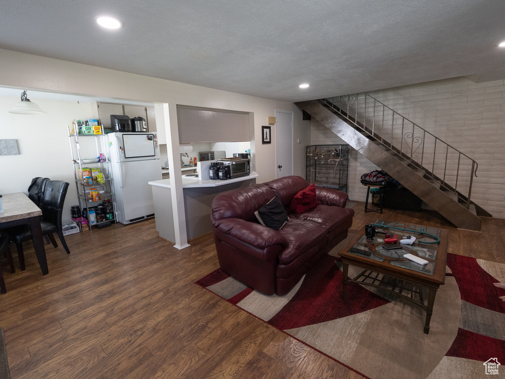 Living room with wood finished floors, stairs, and recessed lighting