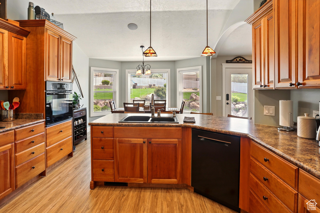 Kitchen with black appliances, a sink, light wood-style flooring, hanging light fixtures, and wine cooler