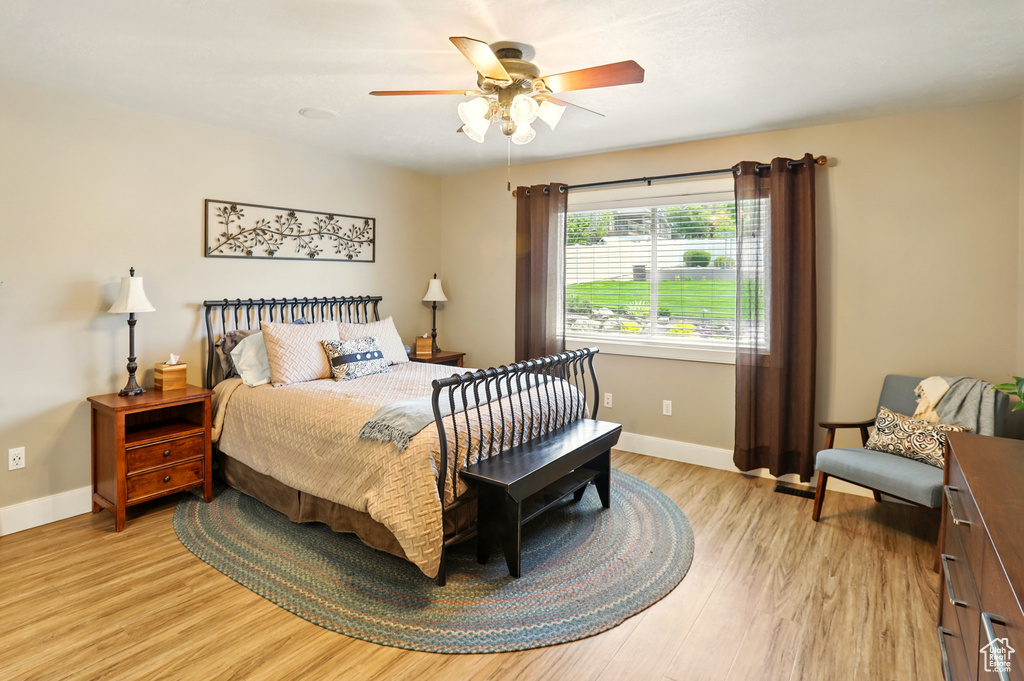 Bedroom featuring light wood-style floors, baseboards, and ceiling fan