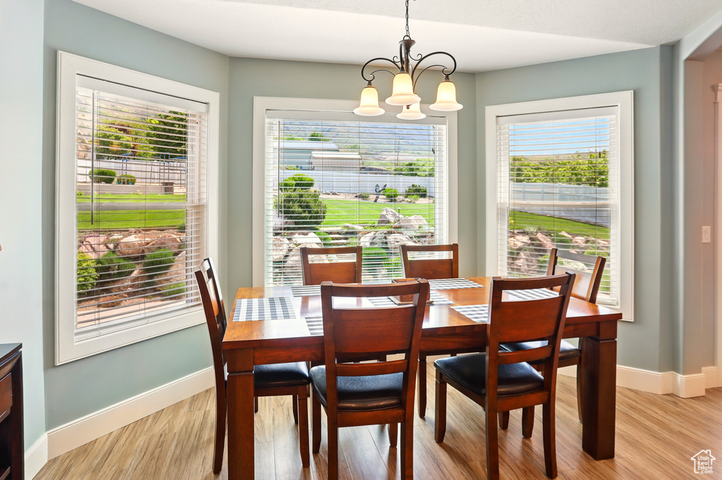 Dining space with healthy amount of natural light, light wood-style floors, a chandelier, and baseboards