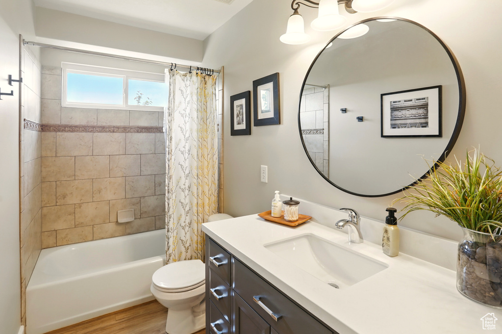 Full bath with toilet, wood finished floors, vanity, and shower / bath combo