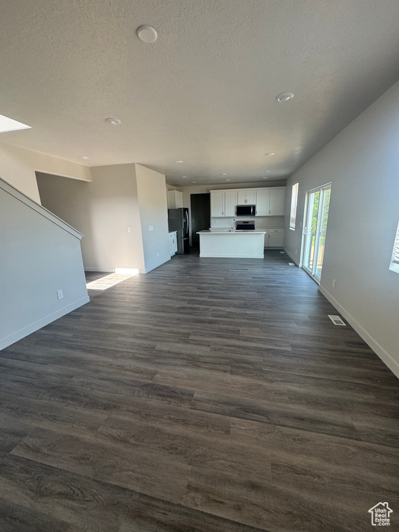 Unfurnished living room featuring dark wood finished floors, recessed lighting, and a textured ceiling