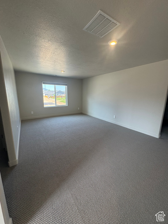 Carpeted empty room featuring baseboards and a textured ceiling