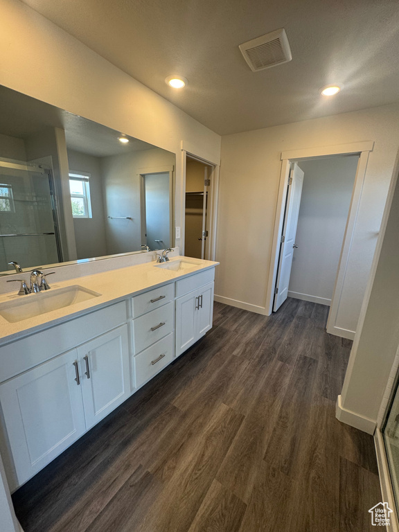 Bathroom featuring a stall shower, double vanity, wood finished floors, and recessed lighting