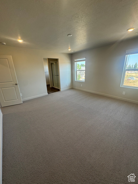Spare room with a textured ceiling, dark carpet, and recessed lighting