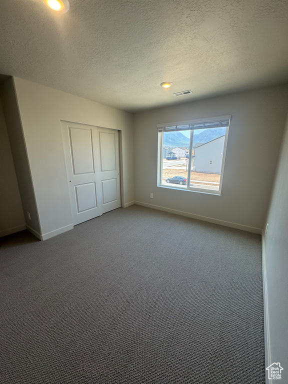 Unfurnished bedroom featuring carpet flooring, a textured ceiling, a closet, and recessed lighting
