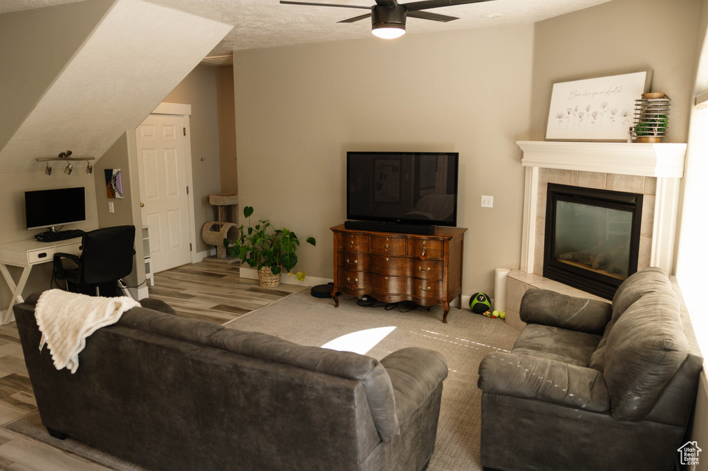 Living area featuring a ceiling fan, a fireplace, wood finished floors, and baseboards