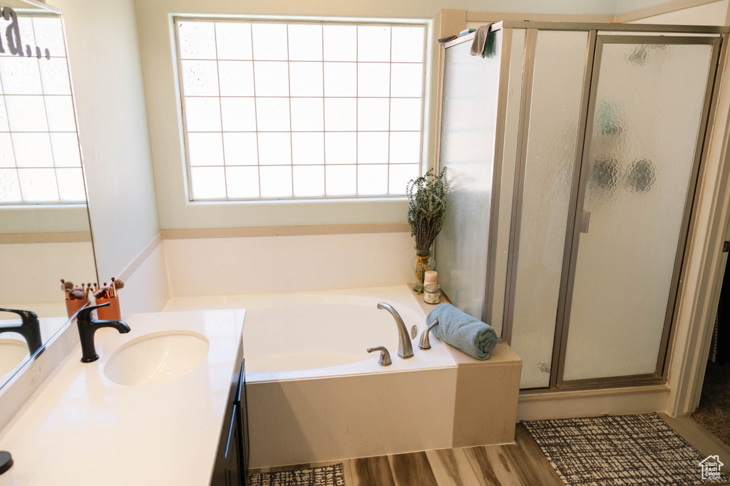 Bathroom with a garden tub, a shower stall, vanity, and wood finished floors