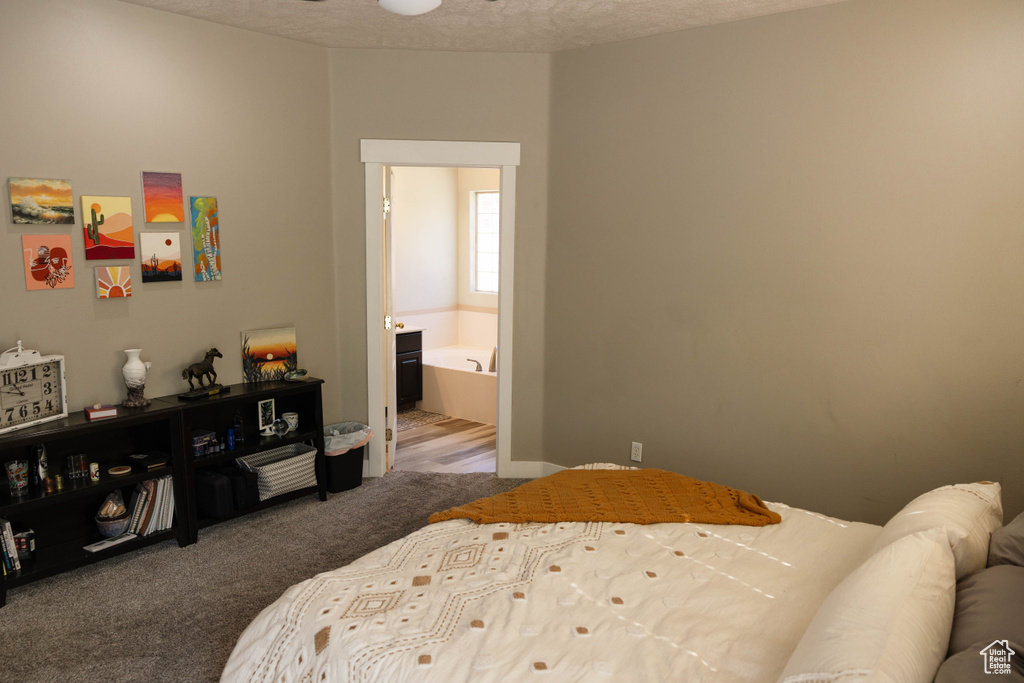 Bedroom featuring a textured ceiling, carpet flooring, and ensuite bathroom