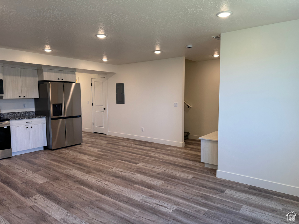 Kitchen featuring stainless steel appliances, electric panel, dark wood-style flooring, baseboards, and a textured ceiling