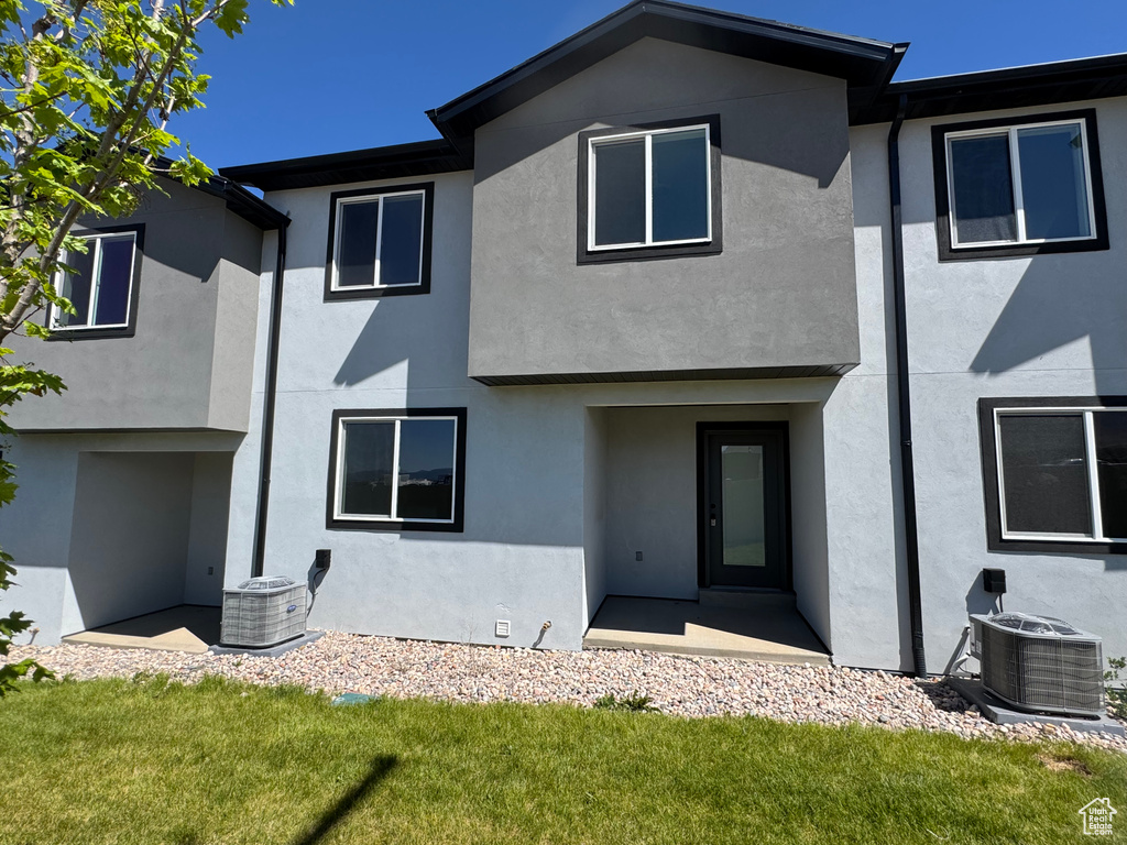 Rear view of property with stucco siding and central AC