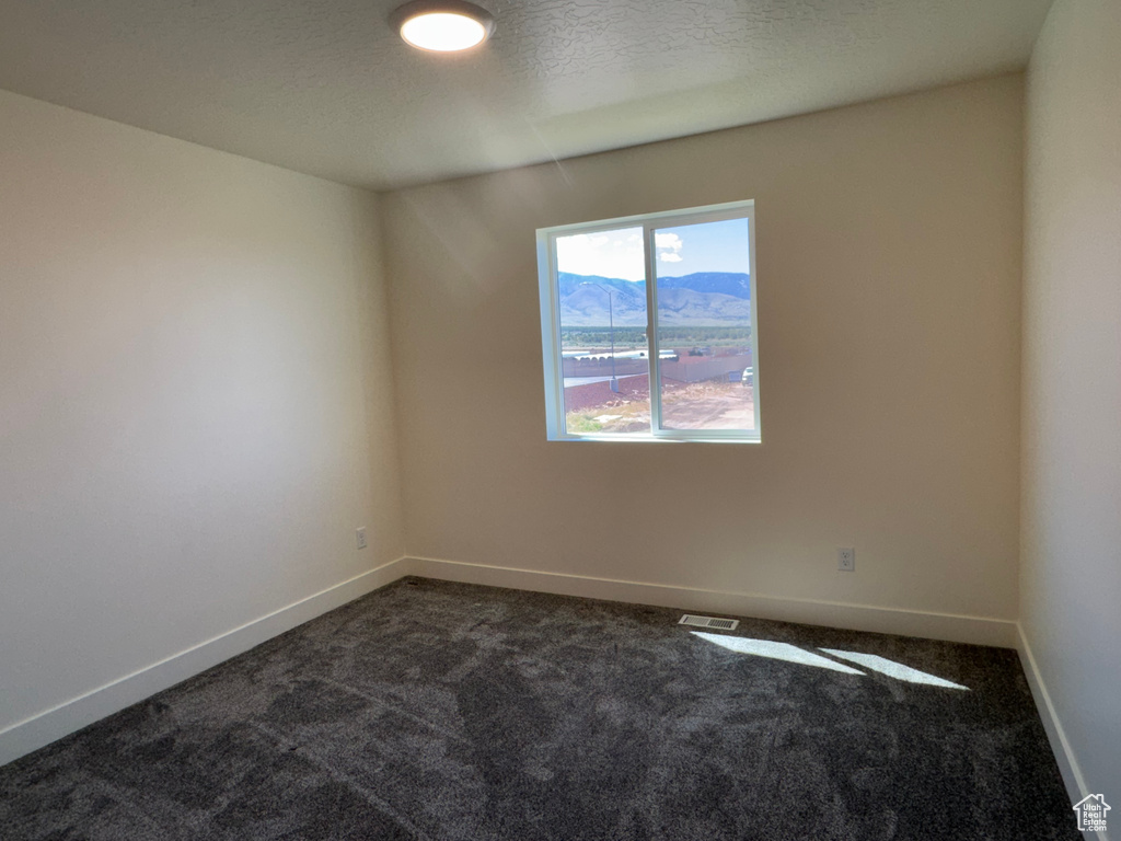 Unfurnished room featuring dark colored carpet and baseboards