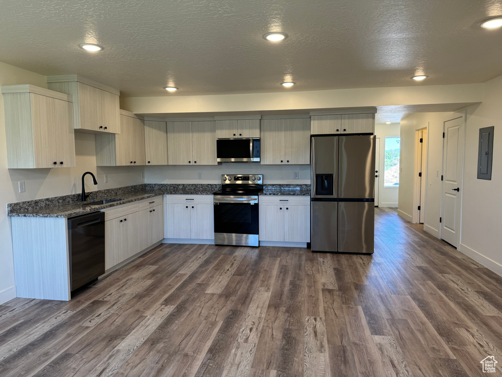 Kitchen with appliances with stainless steel finishes, a sink, dark wood-style flooring, electric panel, and a textured ceiling