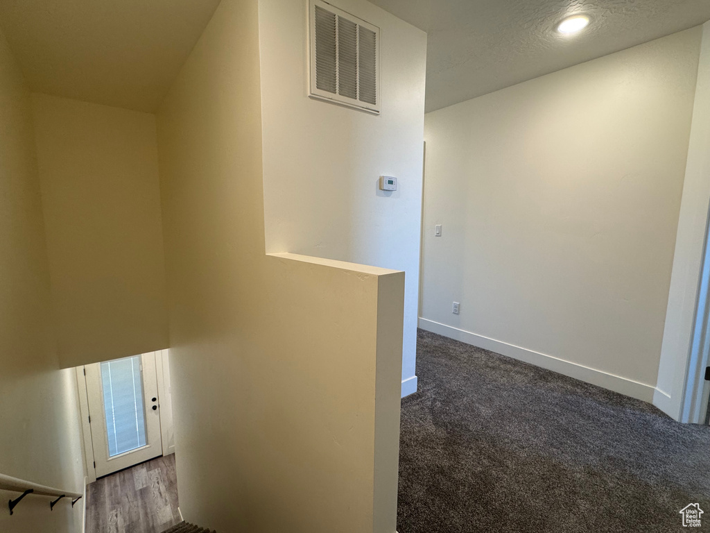Hall featuring baseboards, an upstairs landing, dark colored carpet, and recessed lighting