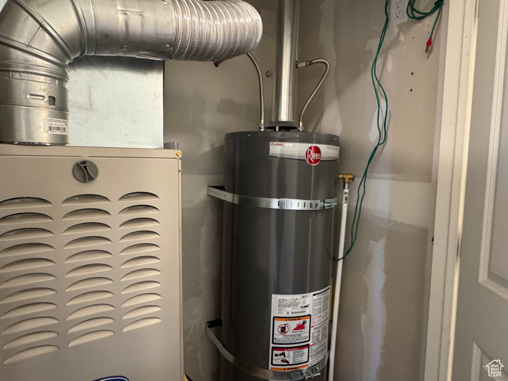 Utility room featuring strapped water heater