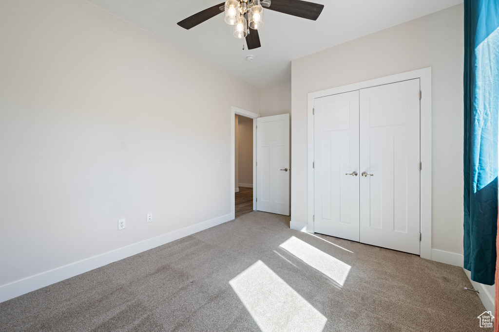 Unfurnished bedroom featuring carpet, baseboards, ceiling fan, and a closet