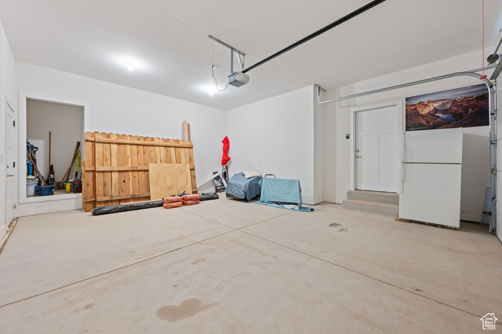 Garage featuring freestanding refrigerator and a garage door opener