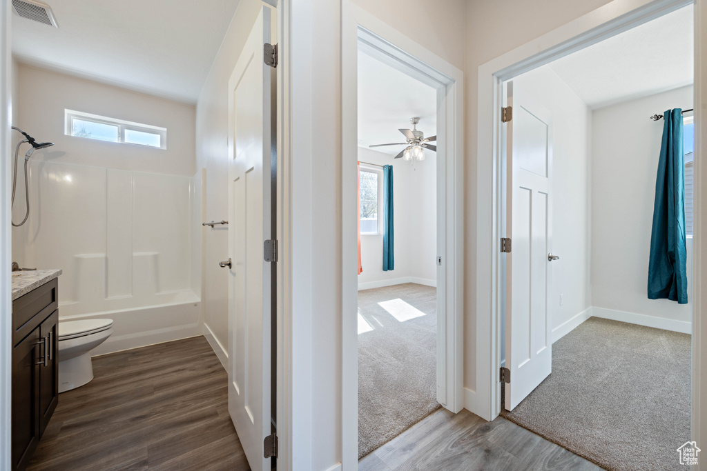 Full bathroom with vanity, wood finished floors, ceiling fan, toilet, and baseboards