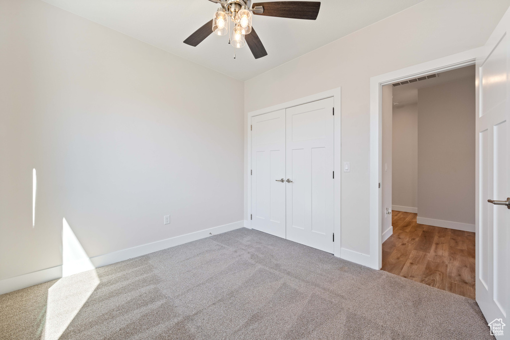 Unfurnished bedroom featuring carpet flooring, baseboards, a closet, and a ceiling fan