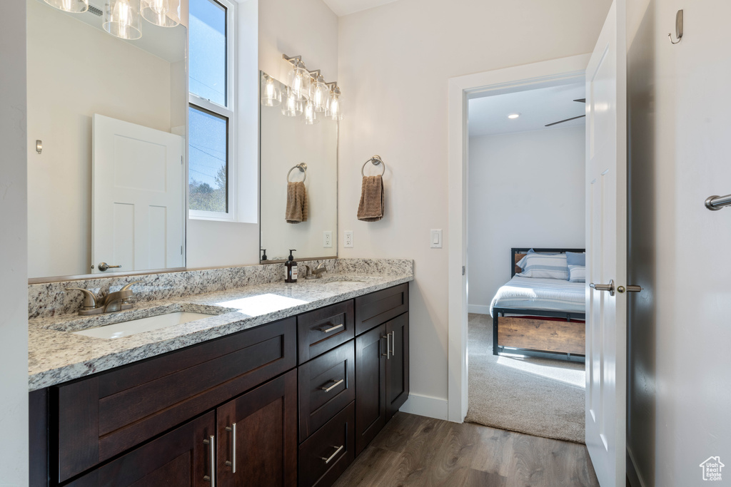 Bathroom featuring wood finished floors, double vanity, ensuite bath, and baseboards