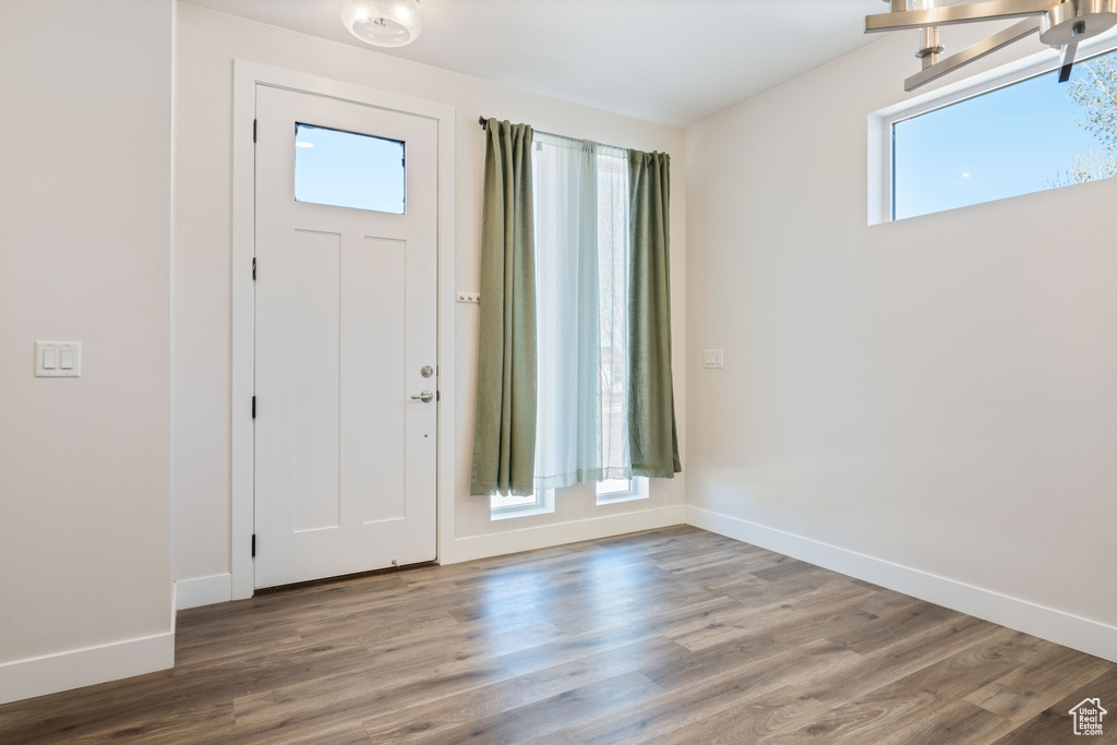 Foyer entrance with wood finished floors, baseboards, and a chandelier