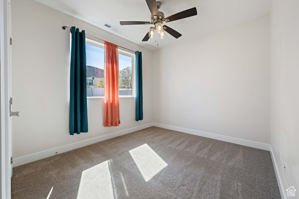 Carpeted spare room with baseboards and ceiling fan