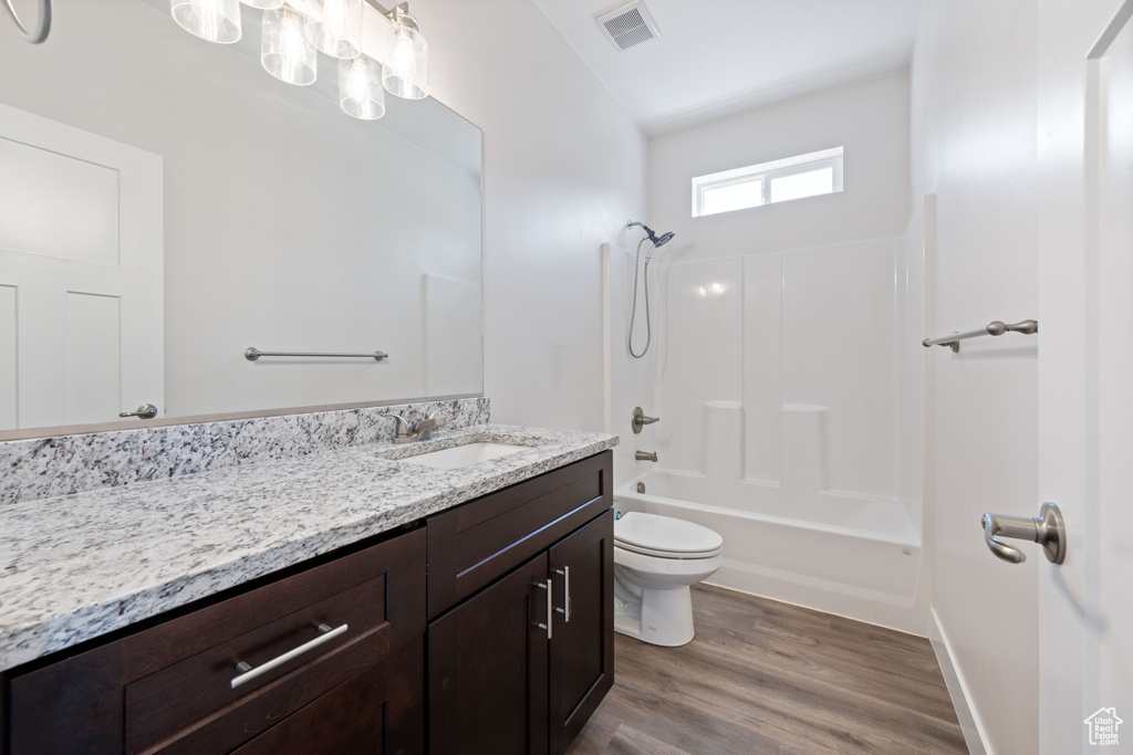 Full bath featuring toilet, wood finished floors, vanity, and shower / bath combination