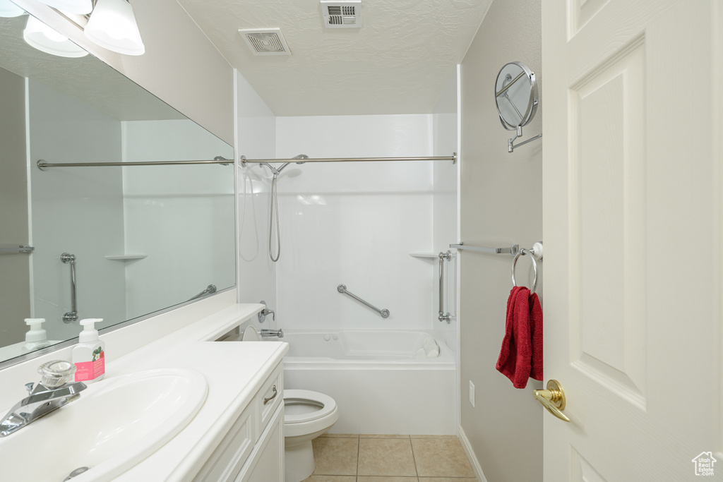 Bathroom with tile patterned flooring, toilet, vanity, shower / bathtub combination, and a textured ceiling
