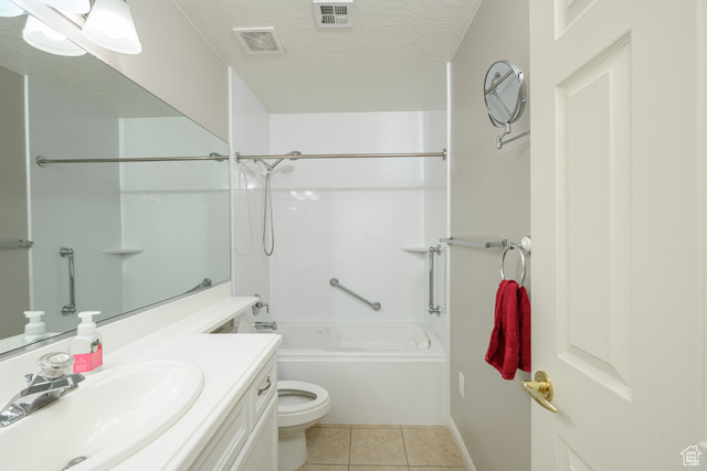 Full bathroom featuring tile patterned floors, toilet, vanity, tub / shower combination, and baseboards