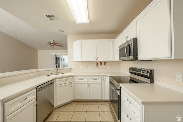 Kitchen featuring stainless steel appliances, light tile patterned flooring, a sink, and white cabinets