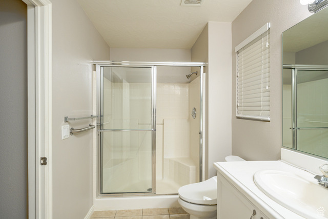 Full bath featuring a shower stall, toilet, tile patterned flooring, and vanity