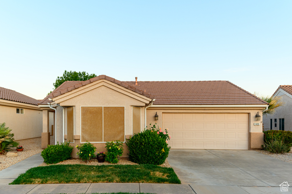 Ranch-style home with concrete driveway, an attached garage, and a tile roof