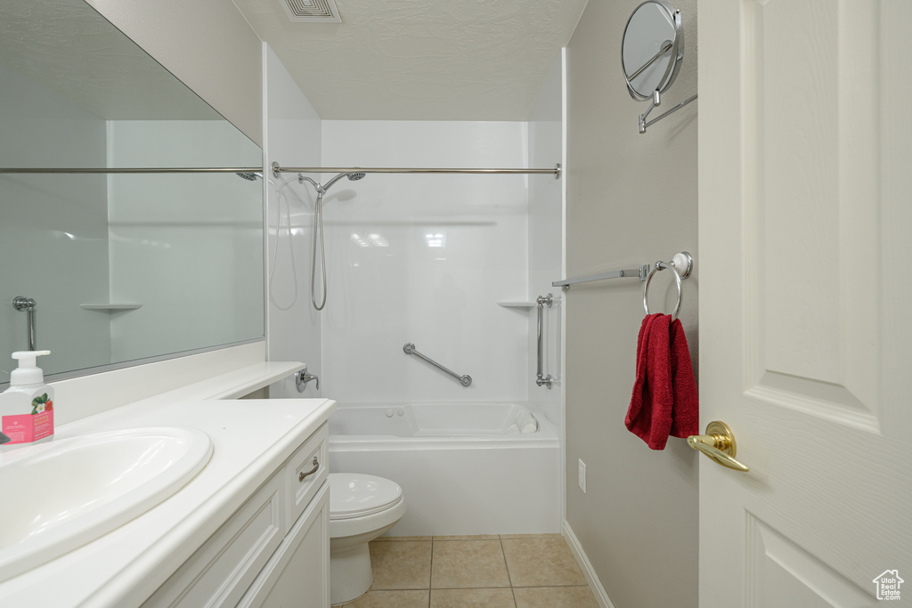 Bathroom featuring toilet, tile patterned floors, vanity, shower / bathtub combination, and baseboards