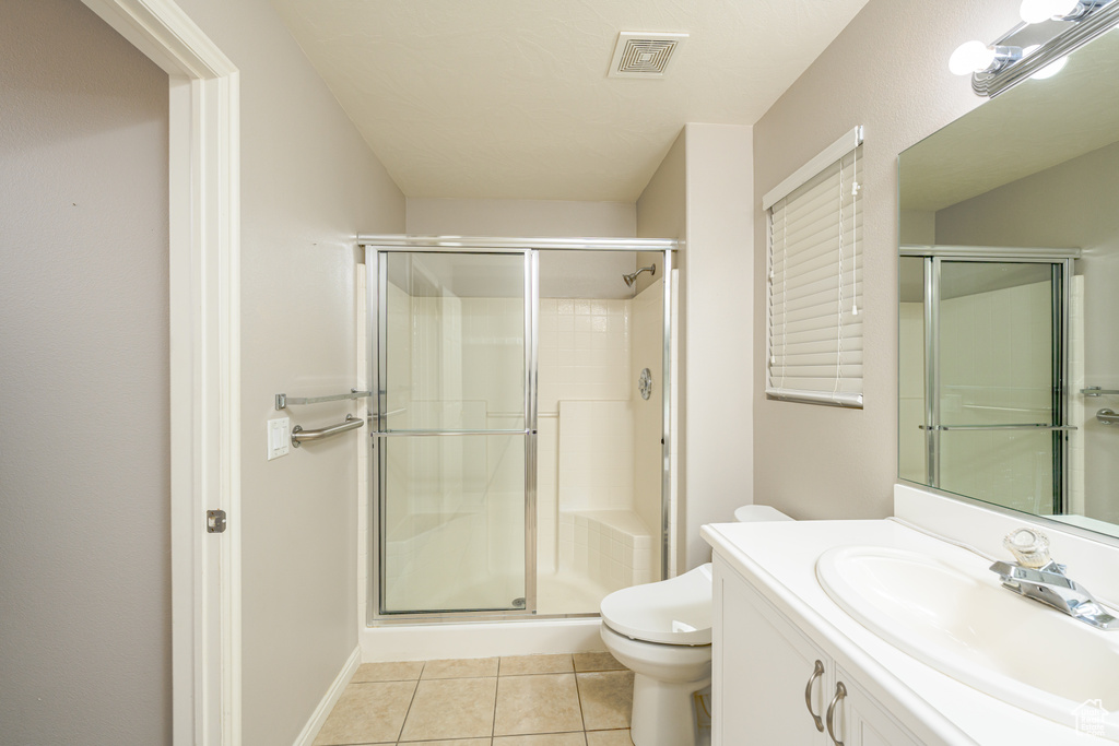 Bathroom featuring a stall shower, toilet, tile patterned flooring, and vanity
