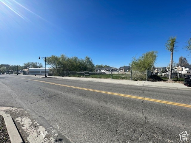 View of asphalt street featuring sidewalks, a residential view, and curbs
