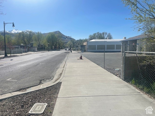 View of road with street lighting, a mountain view, sidewalks, and curbs