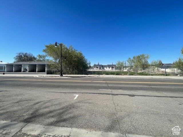 View of asphalt road with sidewalks, street lights, and curbs