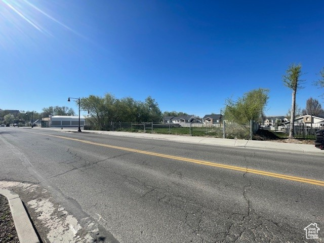 View of asphalt road with sidewalks, street lighting, a residential view, and curbs