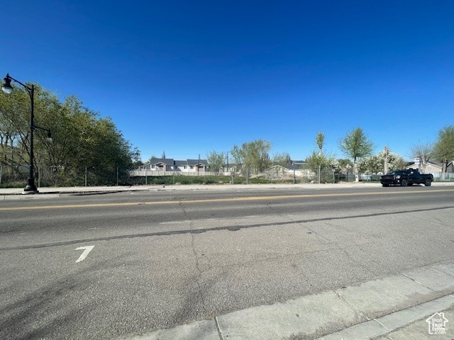 View of asphalt street with sidewalks, curbs, and street lights